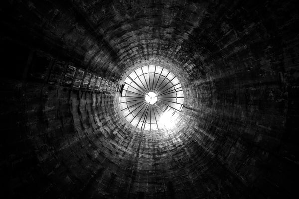 Black and white photograph looking up at the interior of a grain silo on a former dairy farm.