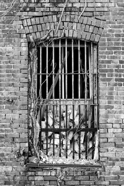 Black and white photograph of an exterior barred window of the abandoned 1894 brick jail in Tunica, Mississippi.
