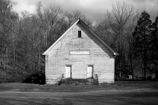 Black and white photograph of an abandoned old church building with two doors found along a country road in the rural American South.
