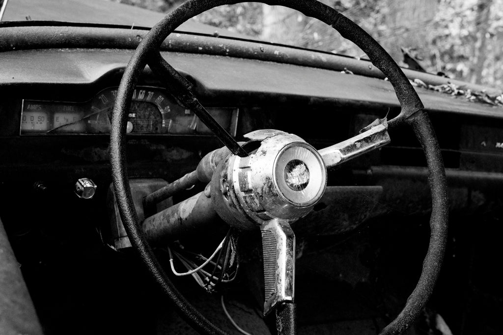 Black and white photograph of the inside of a wrecked and abandoned 1950s era Pontiac automobile found in the forest of the American South.