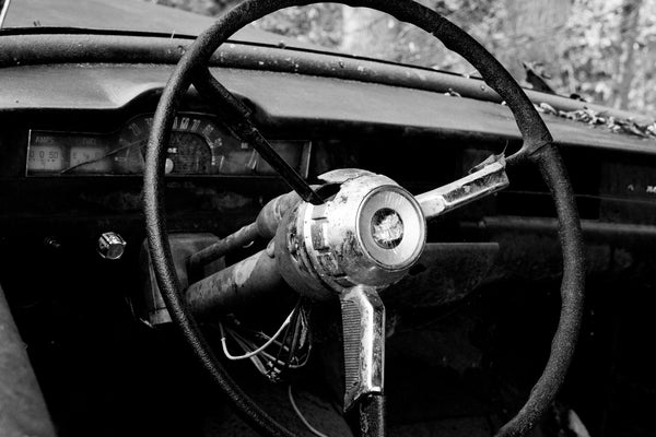 Black and white photograph of the inside of a wrecked and abandoned 1950s era Pontiac automobile found in the forest of the American South.