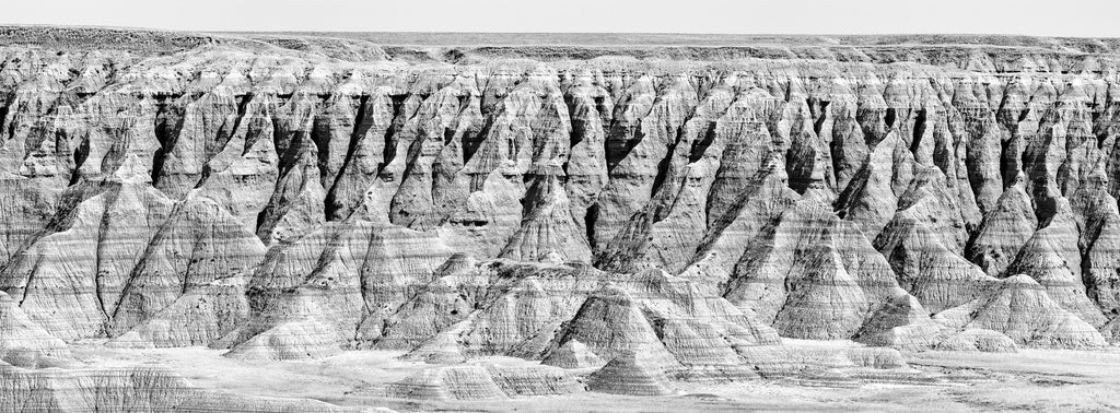 Black and white panoramic landscape photograph of South Dakota's distinctive Badlands landscape.