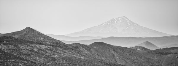 Black and white panoramic landscape photograph of the mountainous landscape surrounding Mount Shasta, a volcanic mountain that is among the tallest in the State of California.