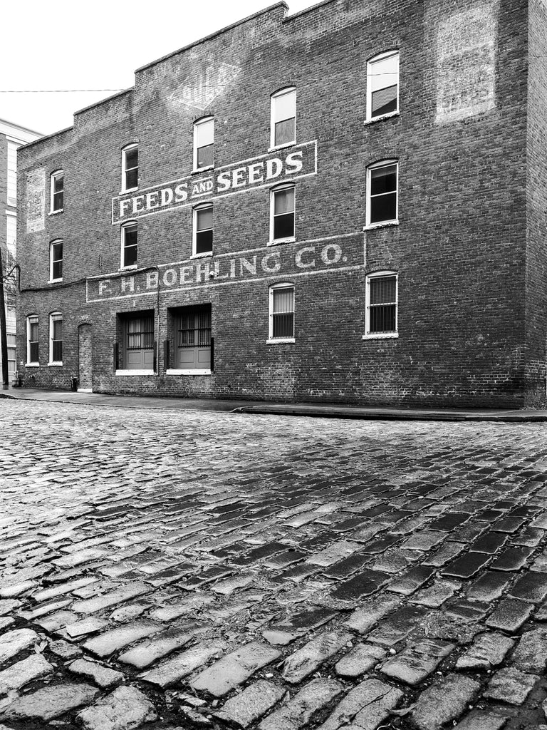 Black and white photograph of the historic F.H. Boehling Feed and Seed store still standing along a cobblestone street in Richmond Virginia.