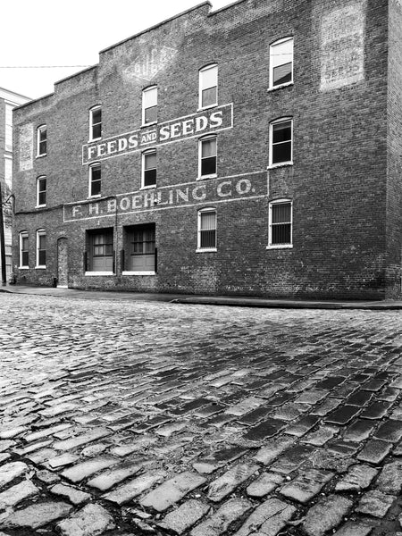 Black and white photograph of the historic F.H. Boehling Feed and Seed store still standing along a cobblestone street in Richmond Virginia.