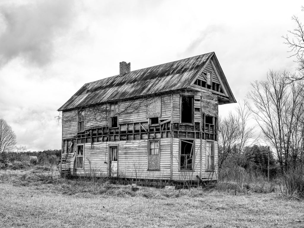 Black and white photograph of a beautiful old ruin of a two-story farm house standing in a barren winter landscape in the American South.