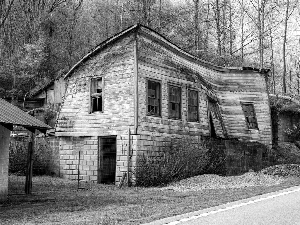 Black and white photograph of a collapsing old storefront with curved and warping walls found along a backroad in the American South.