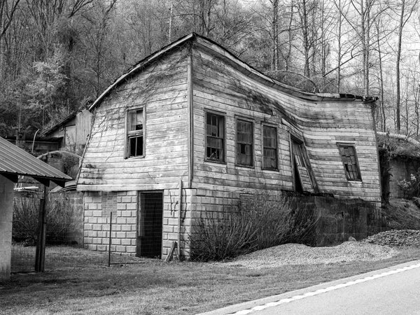 Black and white photograph of a collapsing old storefront with curved and warping walls found along a backroad in the American South.