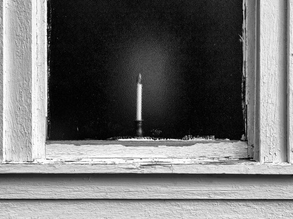 Black and white photograph of a candle seen through the stippled glass of the historic Bethel Church in the beautiful Adirondack region of upstate New York.