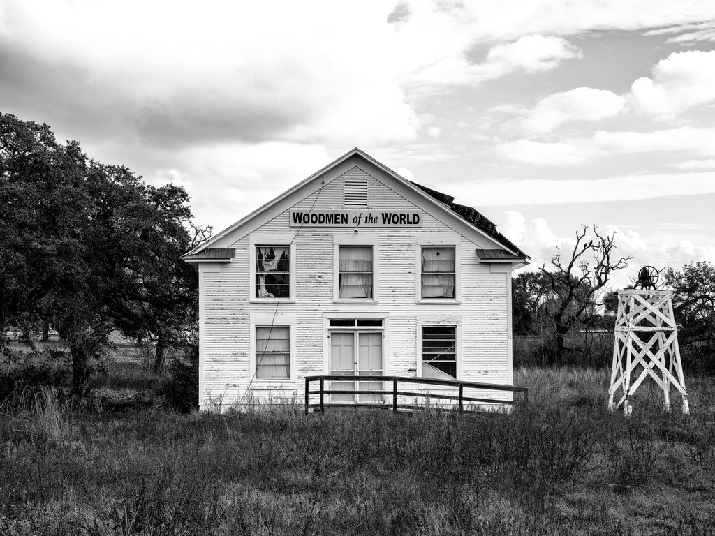 Black and white photograph of the abandoned Woodmen of the World lodge building and bell tower in the small community of Muldoon, Texas.