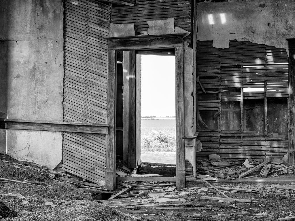 Black and white photograph of the interior of the abandoned one-room County Line Schoolhouse built in 1920 and closed in the 1960s on the wide Kansas prairie.