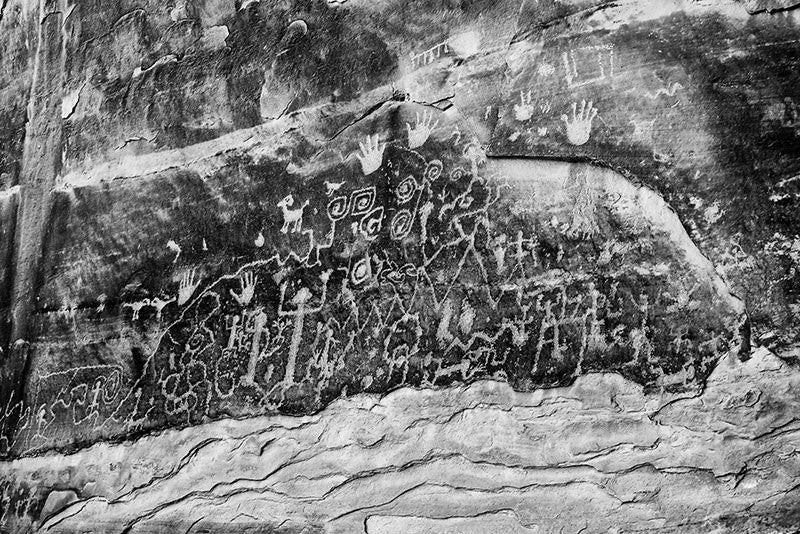 Black and white fine art photograph of ancient petroglyphs that can still be seen at Mesa Verde, Colorado. Petroglyphs are images made by scratching or carving into stone. These glyphs tell the origin story of the Pueblo people.