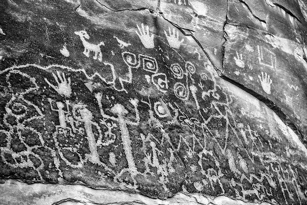Black and white fine art photograph of ancient petroglyphs that can still be seen at Mesa Verde, Colorado. Petroglyphs are images made by scratching or carving into stone. These glyphs tell the origin story of the Pueblo people.