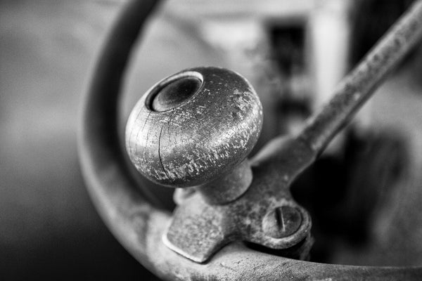 Black and white photograph of the steering wheel with a handle knob on a historic farm tractor.