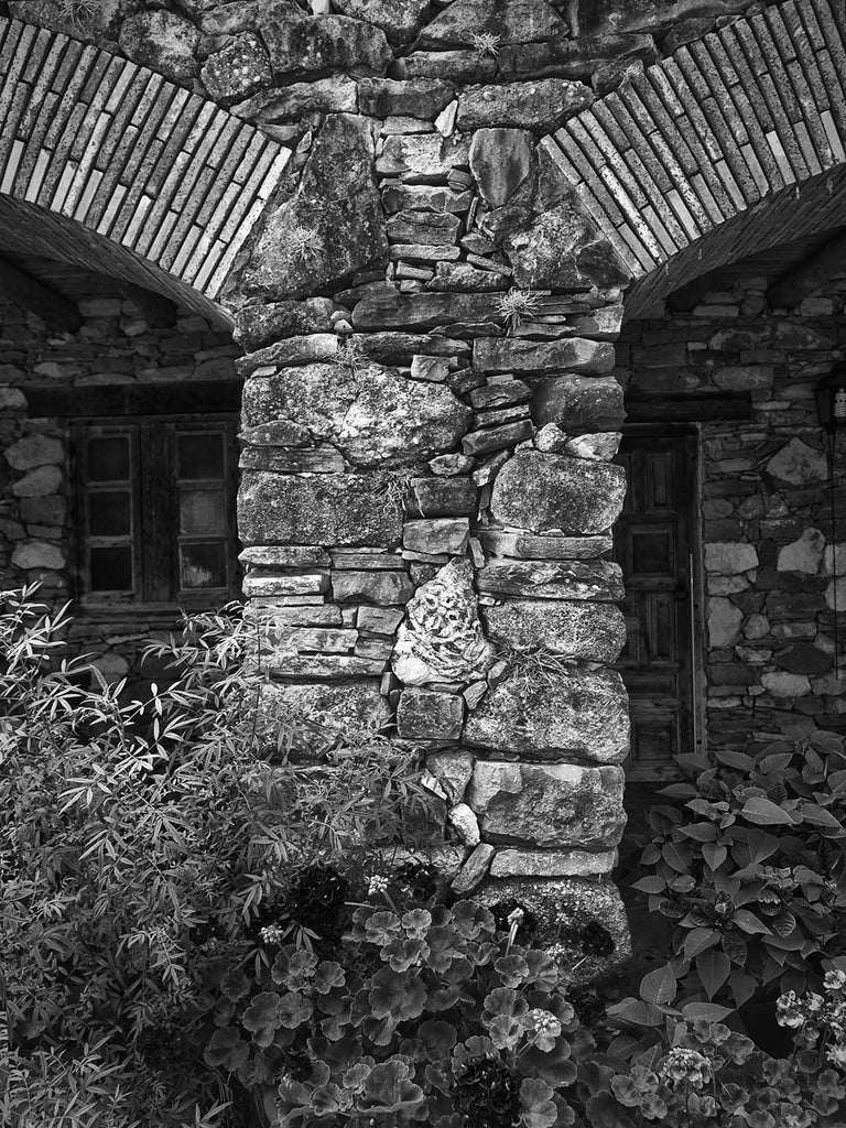 Black and white architectural photograph of the rustic limestone arches at the old Spanish Mission Espada, built in the 1700s, in San Antonio, Texas.
