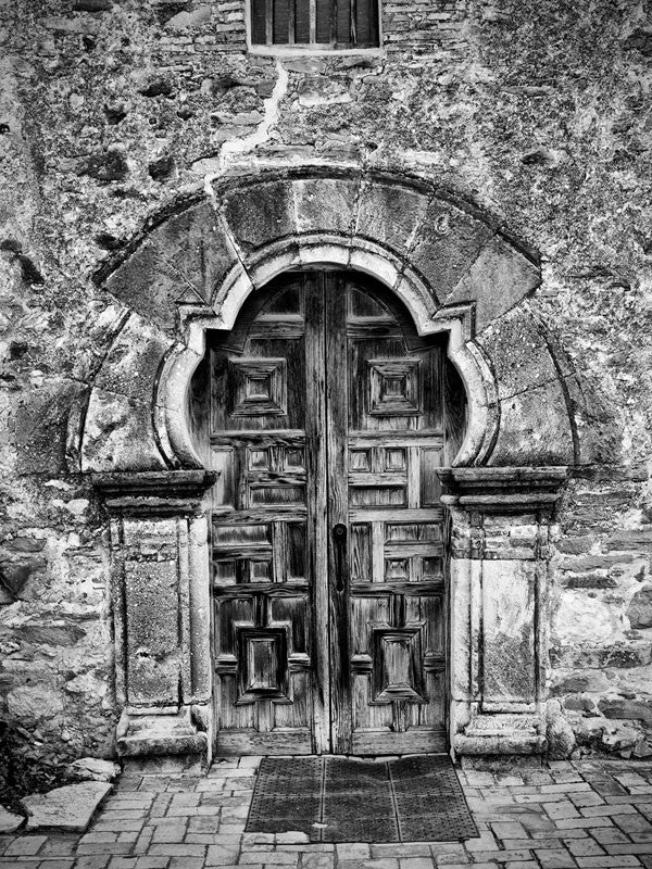 Black and white architectural photograph of the carved wooden front doors of the old Spanish Mission Espada, built in the 1500s, in San Antonio, Texas.