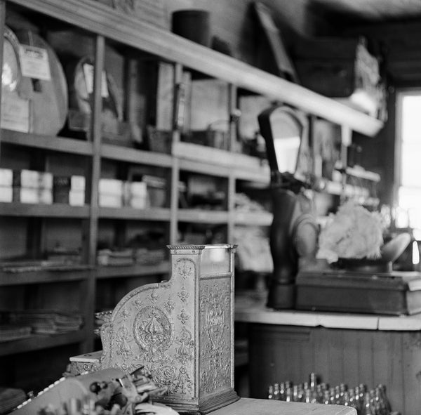 Black and white photograph of the interior of a historic old country store in the southern United States. This photograph was made on medium format film, which has a different look than digital. The print may show some pleasing amounts of film grain. (Square format)
