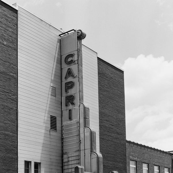 Black and white photograph of a vintage small town Capri Theater marquee sign. This photograph was shot on medium format Cinestill Double-X BwXX black and white film using a vintage Hasselblad camera.