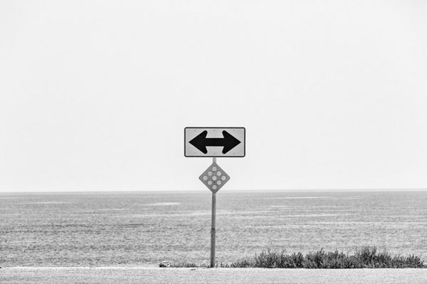 Black and white ladnscape photograph of the Florida coastline, with a road sign as a focal point.