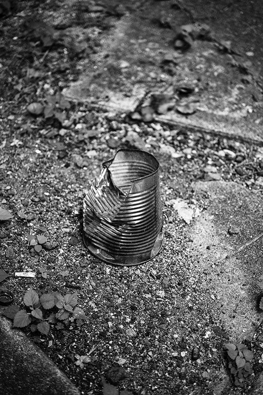 Black and white photograph of a dented tin can used to hold cigarette butts, found in an alley in Birmingham, Alabama.