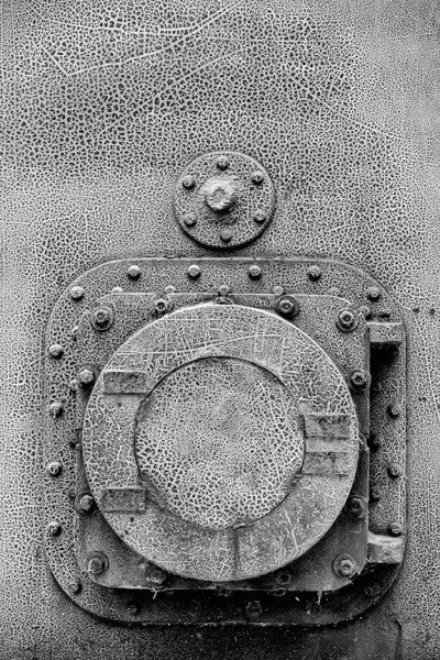Black and white photograph of round door with cracked paint texture at Birmingham's historic Sloss Furnaces.