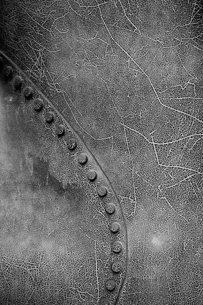 Black and white photograph of cracked paint and rivets on large pipes at Birmingham's historic Sloss Furnaces.