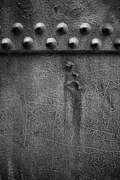 Black and white industrial photograph of big rivets on a textured pipe at Sloss Furnaces in Birmingham, Alabama.