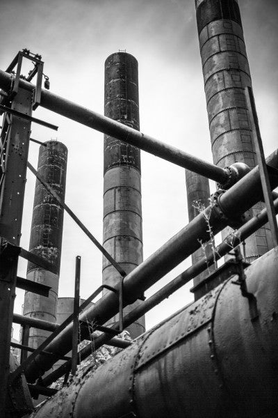 Black and white industrial photograph of pipes and tall smokestacks at Sloss Furnaces in Birmingham, Alabama.
