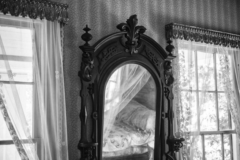 Black and white architectural interior photograph of an ornate wooden mirror inside a bedroom at Birmingham's historic Arlington House.