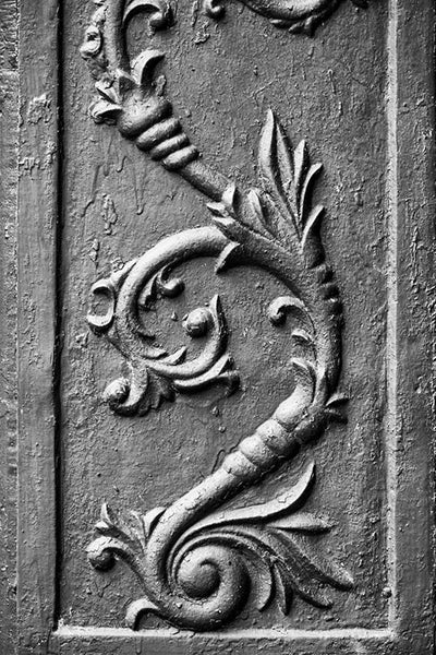 Black and white photograph of an antique cast iron flower architectural decoration, found on the exterior of an old storefront building in a small town.
