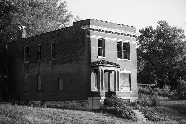 Black and white photograph of an abandoned historic row house in the College Hill neighborhood of St. Louis. Much of the neighborhood dates from the 1870s to the 1890s, and is now sporadically occupied, with many of these grand old structures left abandoned to decay.