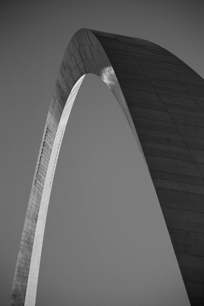 Black and white photograph of the famous St. Louis Gateway Arch, catching the final rays of the setting sun. 