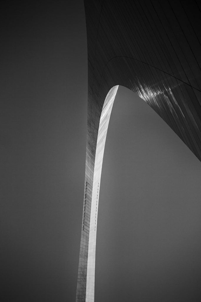 Black and white photograph of the famous St. Louis Gateway Arch, catching the final rays of the setting sun.