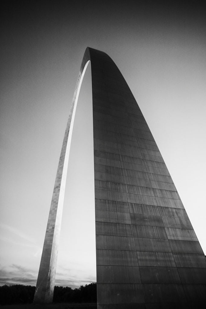 Black and white photograph of the famous St. Louis Gateway Arch catching the last rays of light at sunset. 
