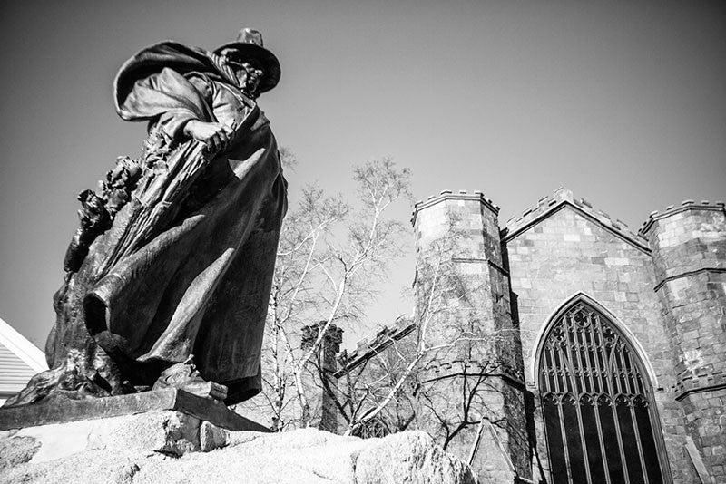 Black and white photograph of the statue of Roger Conant, pilgrim founder of Salem, positioned outside the Salem Witch Museum.