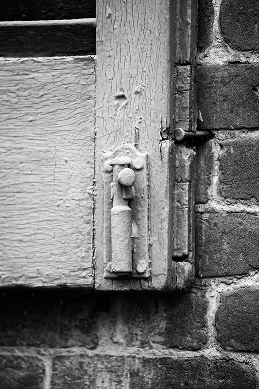 Black and white architectural detail photograph of an antique wooden shutter with cracking paint on an old house in historic Franklin, Tennessee.