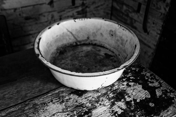 Black and white photograph of a wash basin on a table inside the home of the late blues musician Sleepy John Estes in Brownsville, Tennessee. The small shack where Estes lived has been preserved and relocated to a visitors center near the schoolhouse of Tina Turner, who also hails from Brownsville.