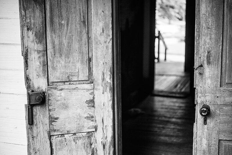 Black and white photograph of French doors on the front of an old Cajun house in Lafayette, Louisiana.