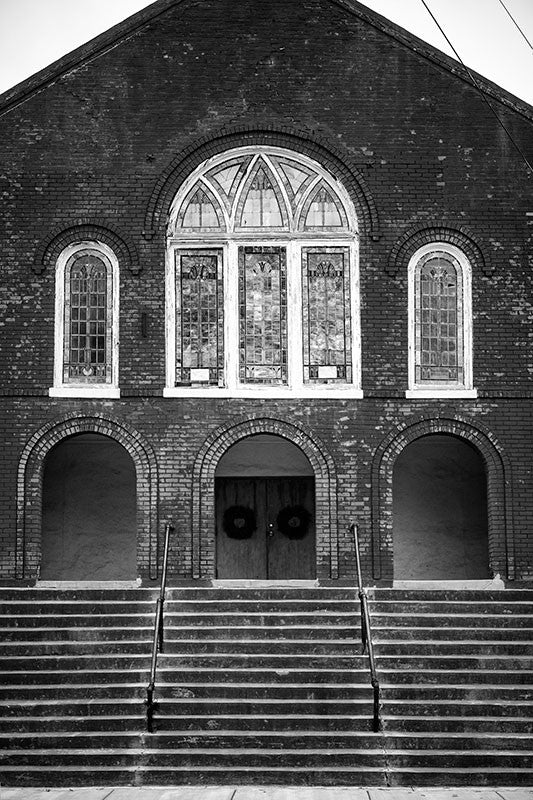 Black and white photograph of the steps and front of a historic red brick church in downtown Clarksdale, Mississippi.