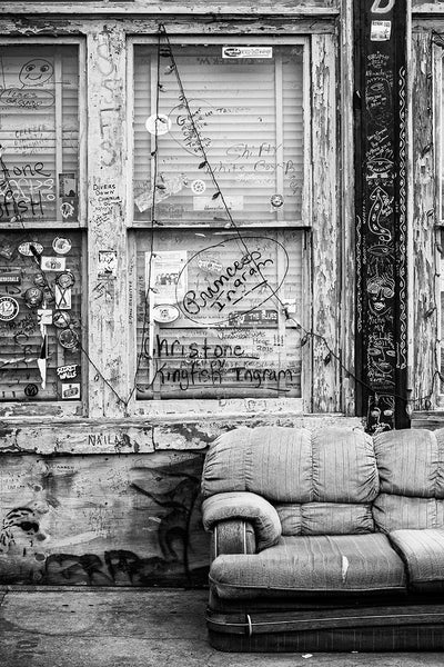 Black and white photograph of the front porch of a downtown Clarksdale, Mississippi, with an old sofa and lots of graffiti.