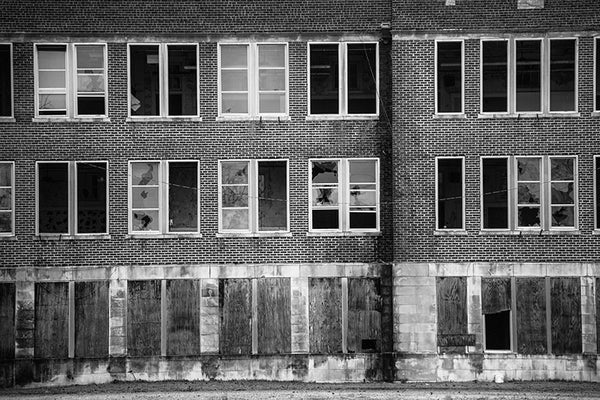 Black and white photograph of rows of broken windows in a very large abandoned school building in Clarksdale, Mississippi.