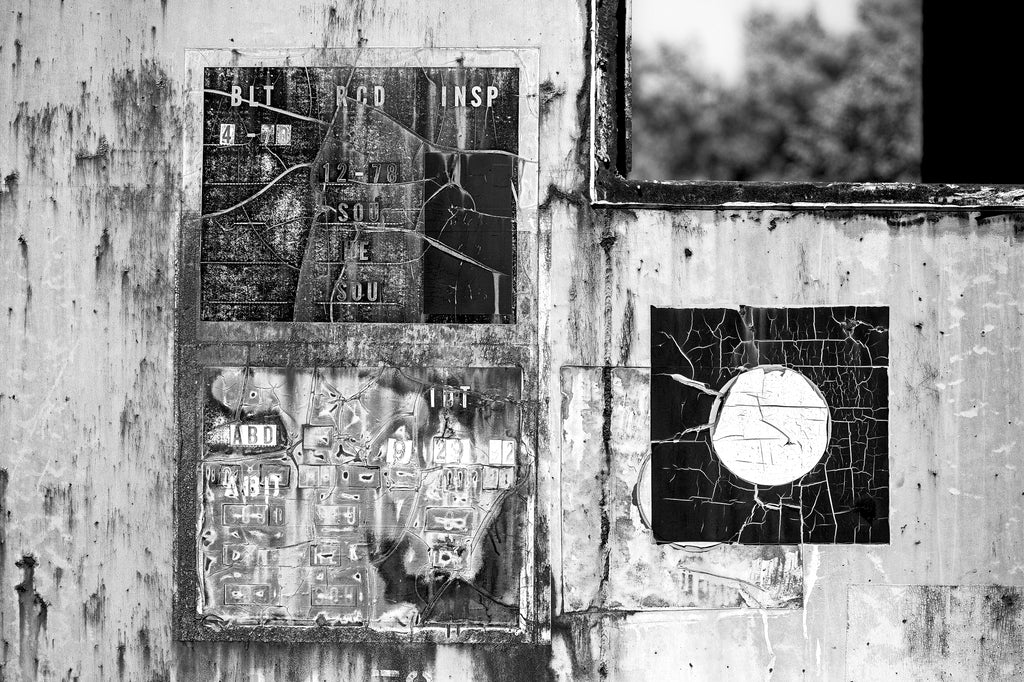 Black and white abstracted photograph of cracked old signs on the side of a rusting abandoned train car.