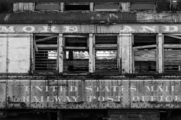Black and white photograph of an abandoned and dilapidated US Mail train car found in Alabama.