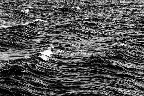 Black and white detail photograph of choppy ocean crests with white caps.
