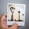 Shown in hand for scale, an original Polaroid photograph taken in San Antonio, Texas, with the sculpture "La Antorcha de la Amistad" by Sebastián in the foreground and the Tower of the Americas in the background.