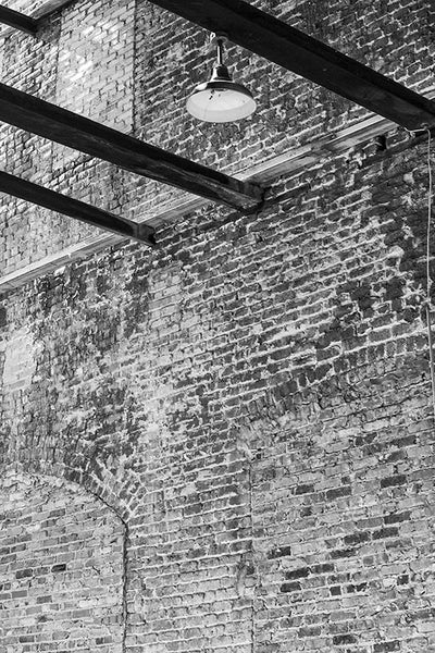 Black and white industrial photograph of an old brick warehouse with a missing roof. 