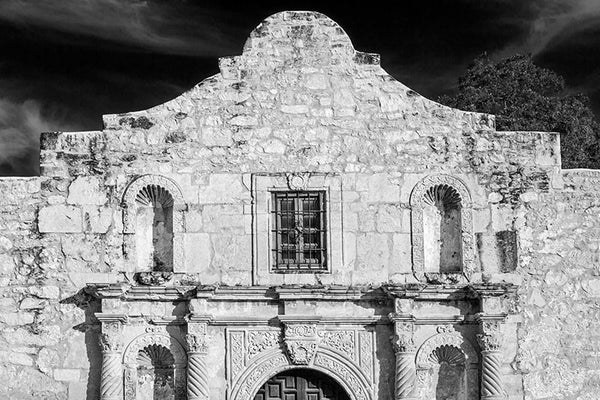 Black and white fine art photograph of the unmistakable front façade one of the most recognizable buildings in the world, the Alamo in San Antonio, Texas. The Alamo is one of San Antonio's old Spanish missions, built as the Misión San Antonio de Valero in 1744. It gained notoriety in 1836, when a small group of Texas freedom fighters (then called Texians), took refuge in the mission for a battle against overwhelming Mexican forces under General Antonio Lopez de Santa Anna. "Remember the Alamo," became a ral