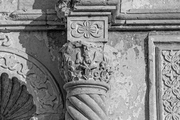 Black and white detail photograph of one of the carved stone columns on the front of the world-famous Alamo in San Antonio, Texas