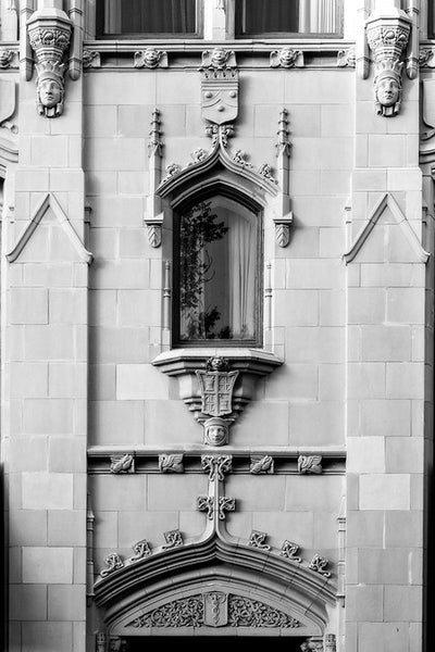 Black and white architectural photograph of the ornate Gothic Revival details on the exterior of The Emily Morgan Hotel in San Antonio, Texas. Details include several human faces carved into the stone work.