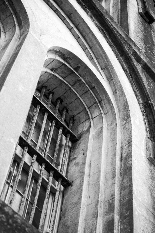 Black and white photograph of rusty iron bars on a second floor window on the front the old Charleston Jail, which was built in 1802 and served until 1939.